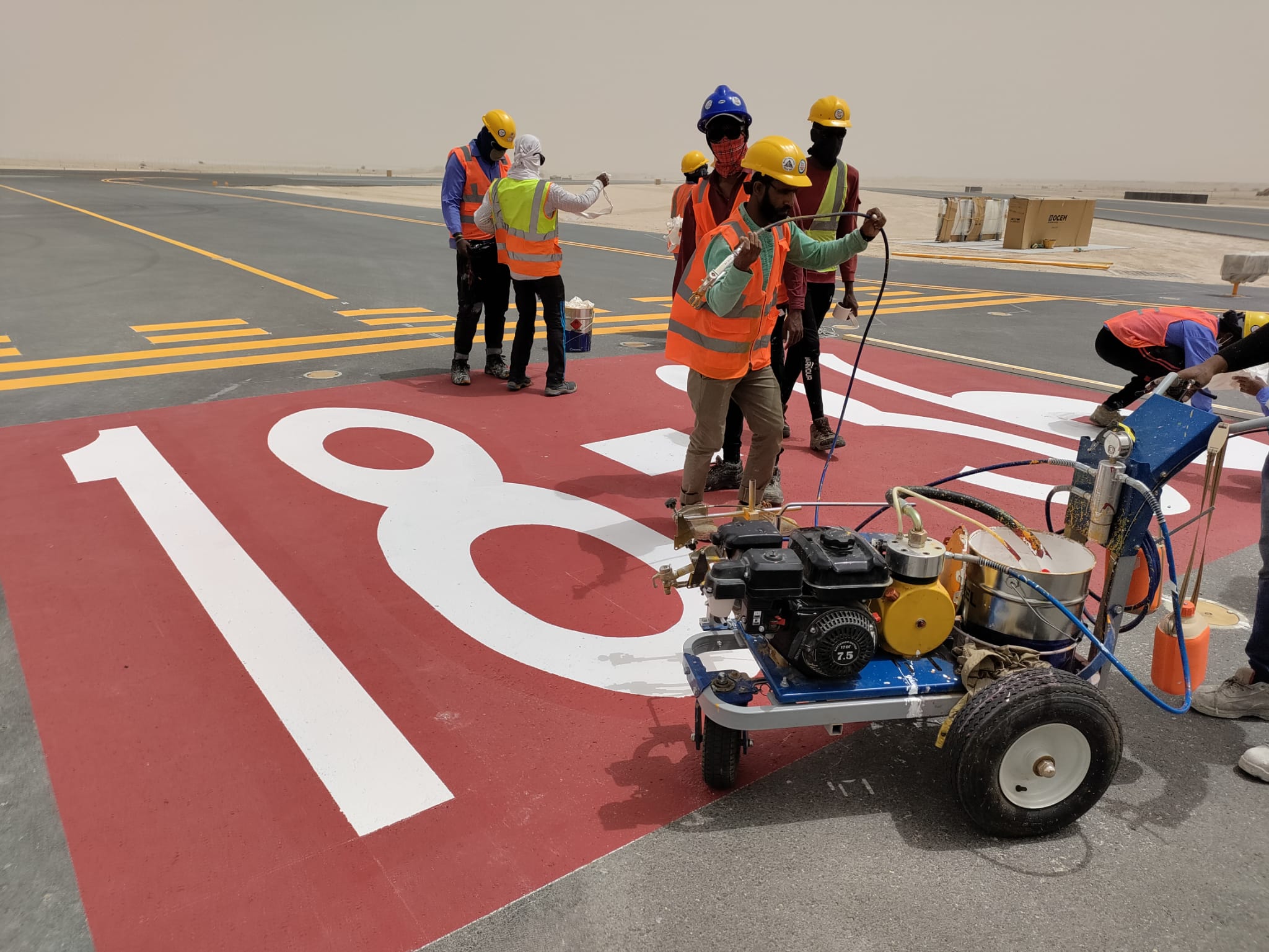 Crew painting a large runway number with a line-marking machine