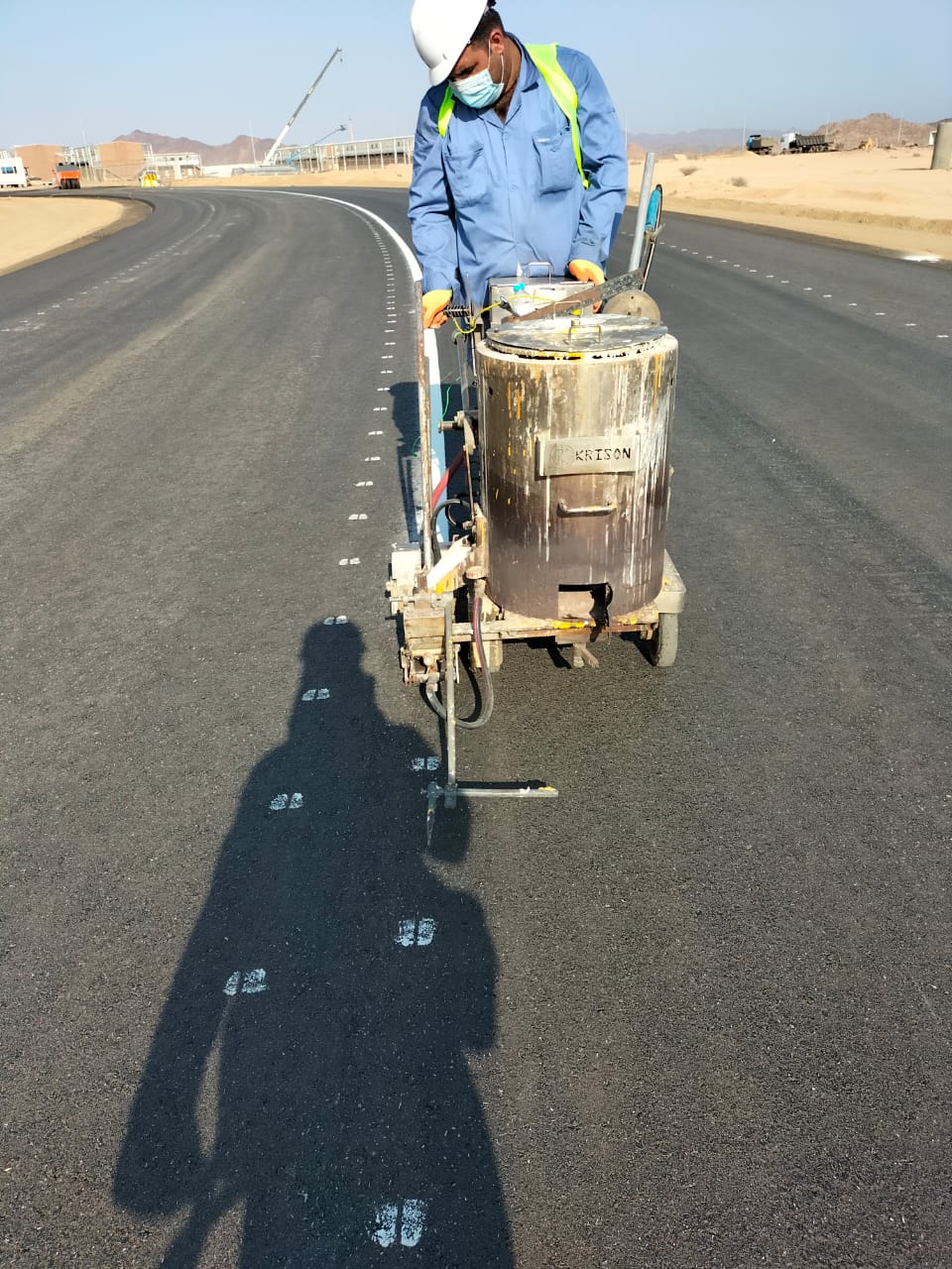 Worker applying road markings with a hand-pushed line-marking machine