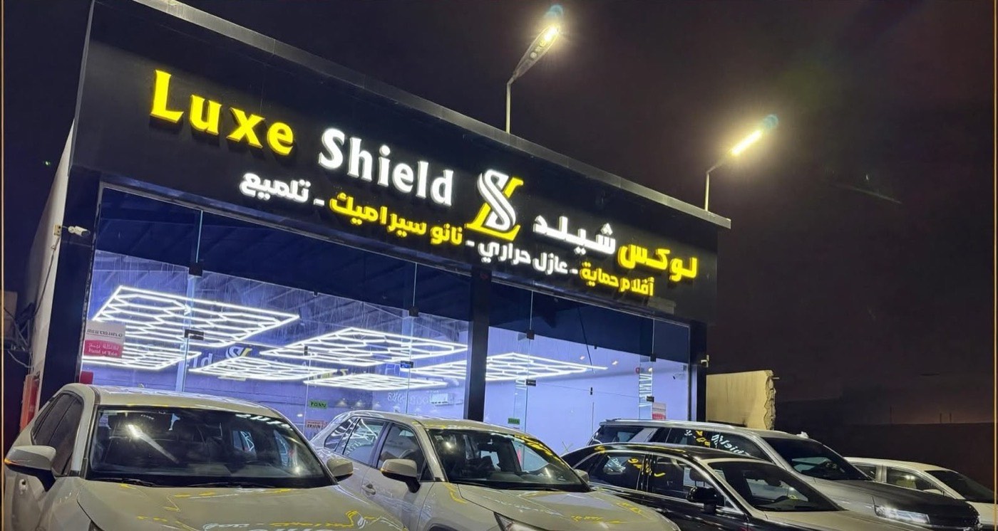 Luxe Shield studio storefront at night, with cars parked outside